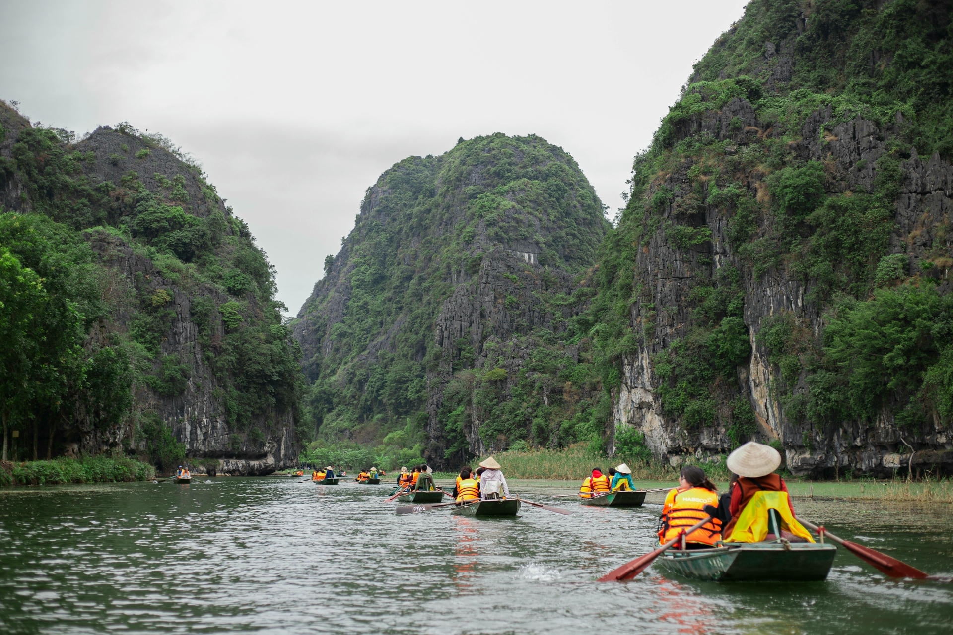 Rowboat gliding through limestone karsts in Trang An, Ninh Binh, Vietnam’s UNESCO World Heritage site for peaceful river tourism