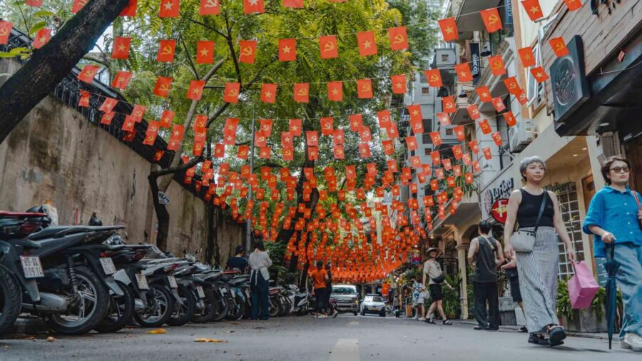 Many Vietnamese flags are hung along the streets of Hanoi. Is hanoi bigger than saigon?