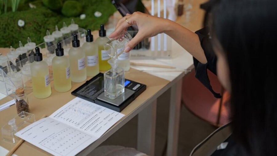 A participant pours fragrance ingredients into a glass bottle while making handmade perfume at a workshop.