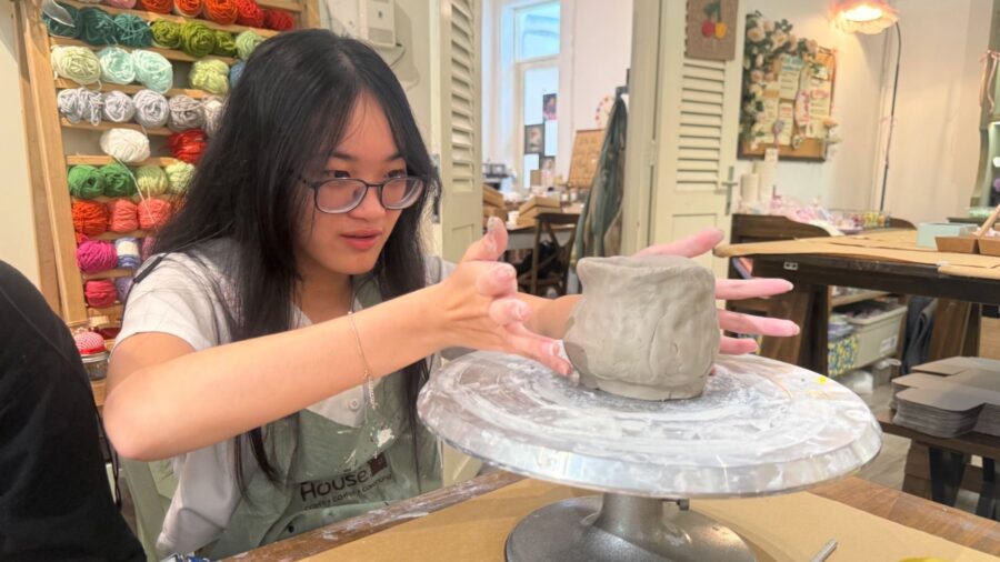 A participant shapes a clay cup by hand during a pottery workshop in Ho Chi Minh City, focusing on the form and surface of the piece.