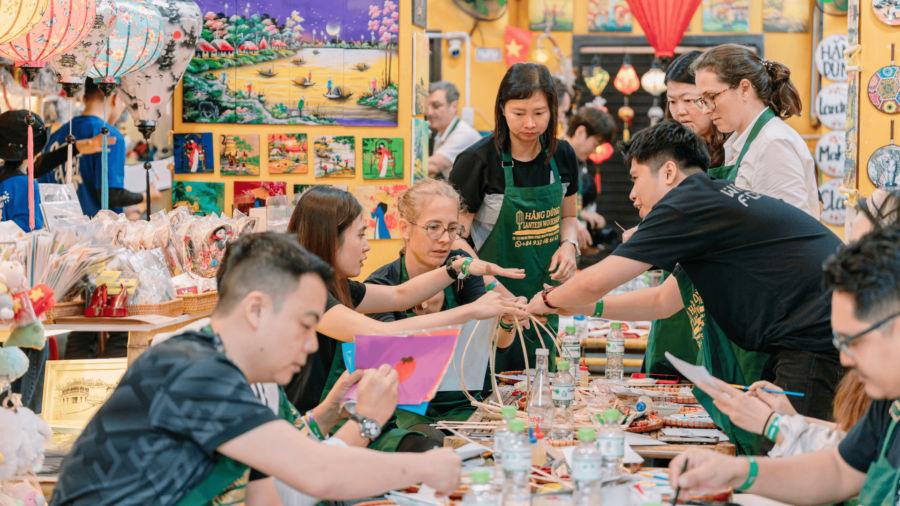 Corporate team bonding activities during a Vietnamese lantern craft workshop with local artisans guiding participants.