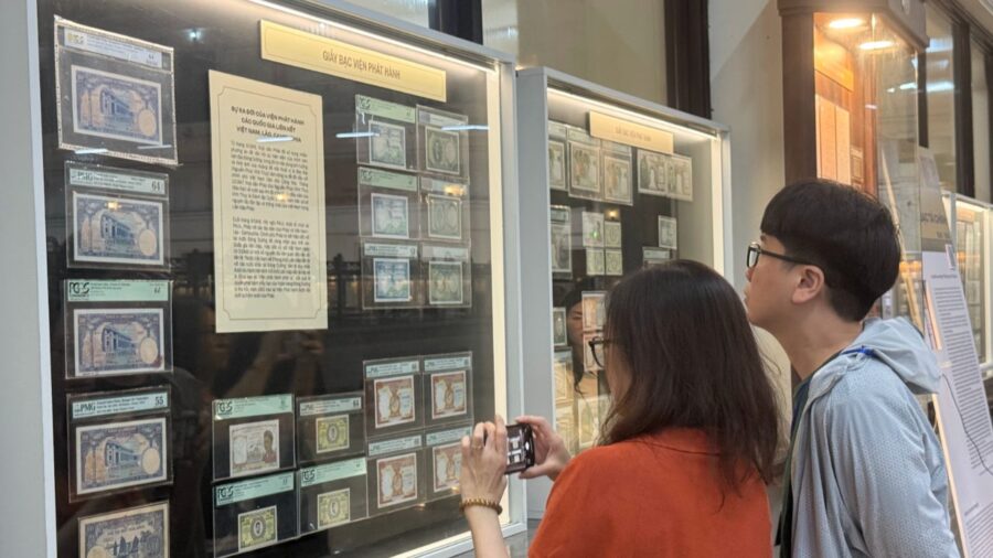 Visitors viewing historical Vietnamese currency displayed in glass cases inside the Vietnamese currency exhibition in Ho Chi Minh City.