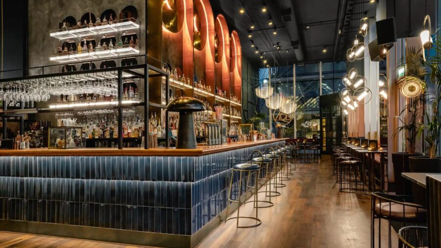 Interior of The Alchemist Cocktail Bar with a long bar counter, modern lighting, and cozy seating in Hanoi
