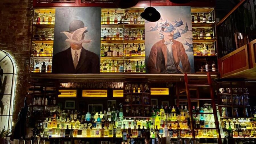 The bar counter at Polite & Co, designed with floor-to-ceiling liquor shelves and large paintings