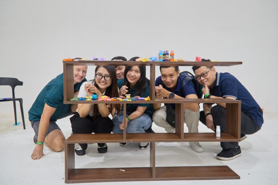Corporate team bonding activities during a creative shelf building challenge, focusing on collaboration and teamwork.