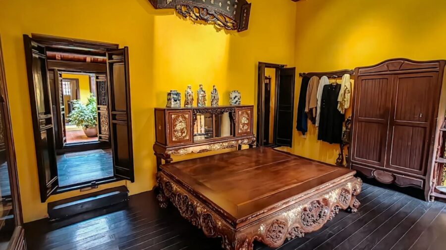 Traditional bedroom featuring an intricately carved wooden bed in a hanoi ancient house