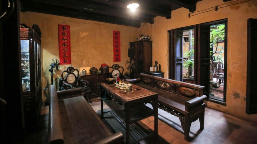 Living room space with antique wooden furniture and red couplets inside a hanoi ancient house.