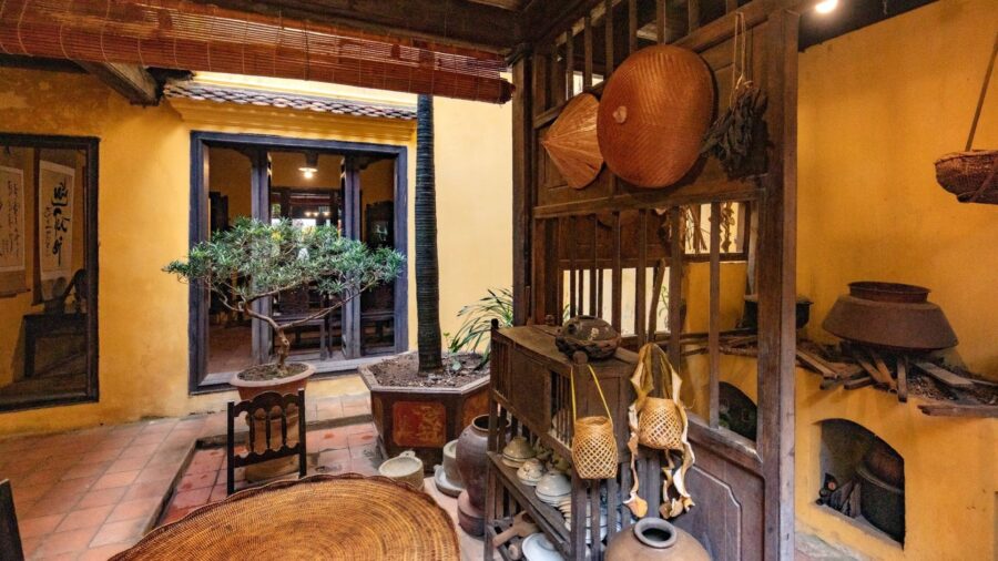 The kitchen area, with its wood-burning stove and wooden dining table, evokes the old-world charm of Hanoi Ancient House
