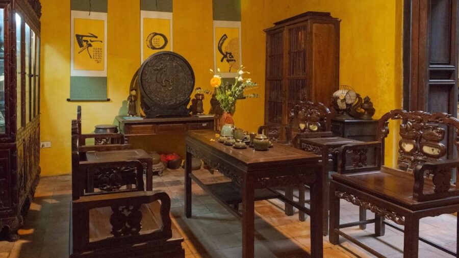 Common living area decorated with flowers and carved wooden furniture in a hanoi ancient house