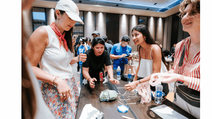 Corporate team bonding activities during a creative straw bridge building challenge focused on teamwork and problem-solving.
